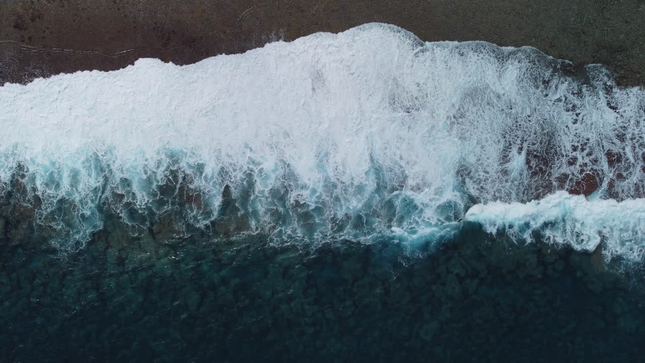 Aerial : Bird’s eye view of stormy waves crashing on coastline of Loyalty islands, New Caledonia