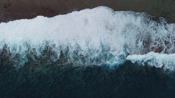 Aerial : Bird’s eye view of stormy waves crashing on coastline of Loyalty islands, New Caledonia