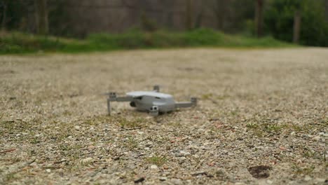 small drone lands on gravelly ground, close up shot