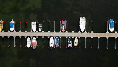 pequeño puerto con muchos barcos pequeños, el hombre camina lentamente a través del muelle, el océano, visby, suecia, dron