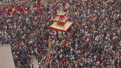 huge crowd of nepali people to witness newari festival at bhaktapur durbar square pulling chariot with unity, people enjoy and celebrate bisket jatra drone shot reveling prosperity of culture in nepal