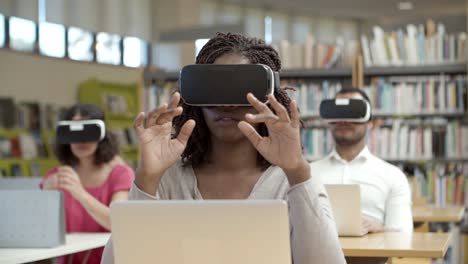 vooraanzicht van opgewonden vrouw die in de bibliotheek zit en vr ervaart