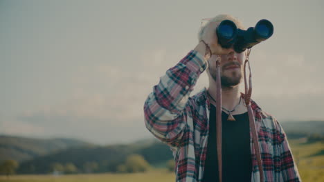 blond man looking through binocular against sky