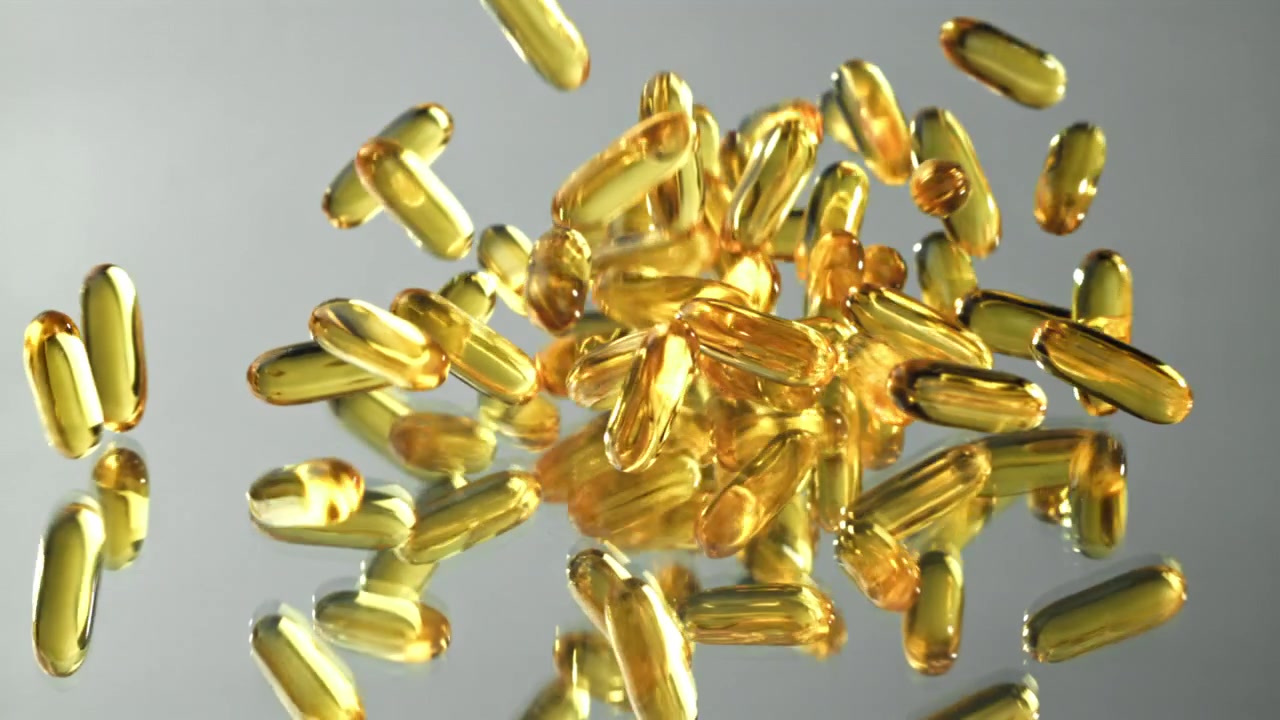 Capsule dorate di Omega 3 che cadono al rallentatore.