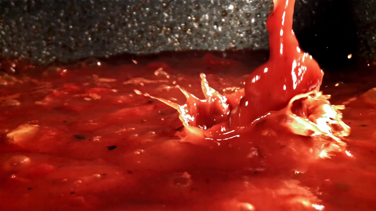 Salsa di pomodoro rosso vivace che sobbolle e schizza al rallentatore