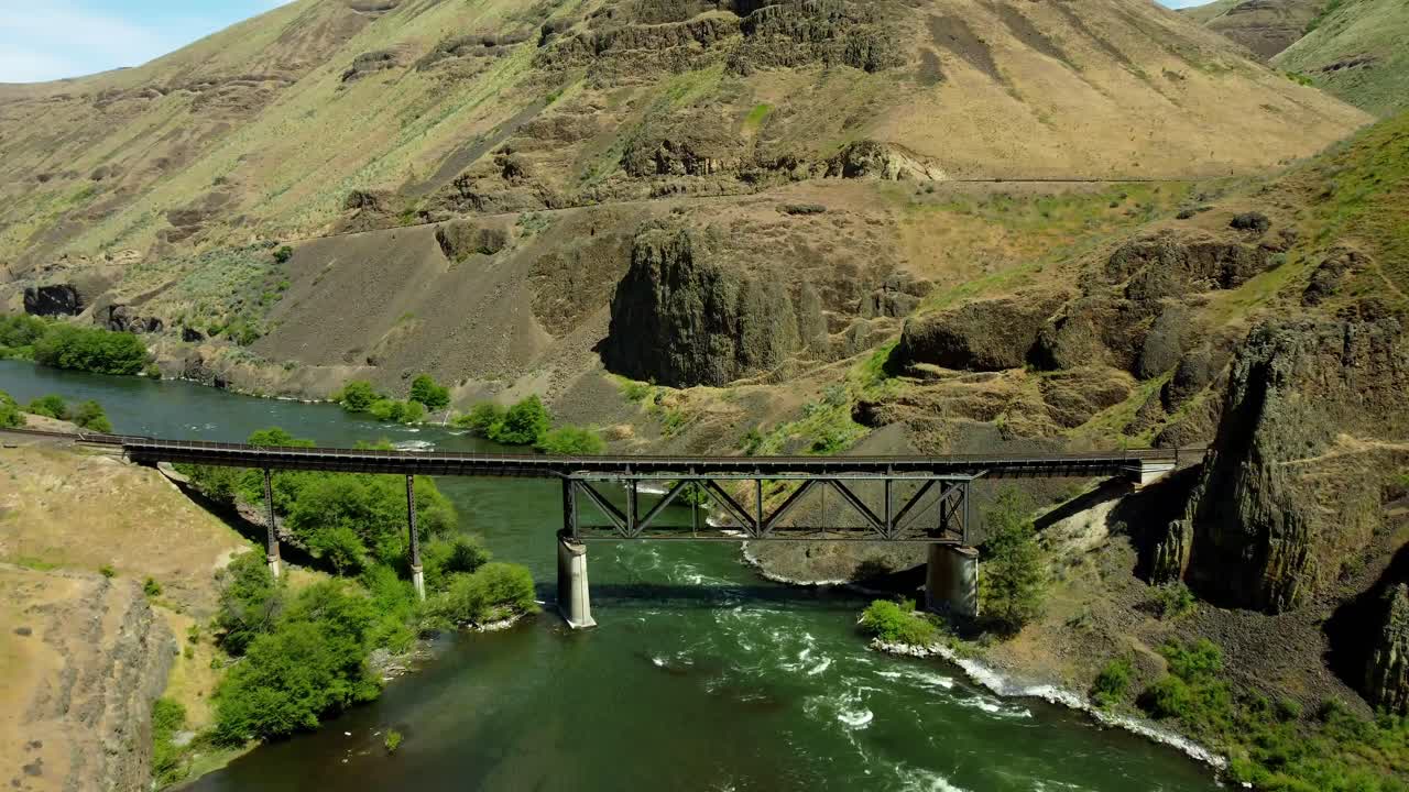 US, Oregon, Maupin, Deschutes River, 2025-05-08 - Drone view on the Deschutes River of a train bridge at Twin Crossings which is two bridges and a tunnel. In north central Oregon in spring