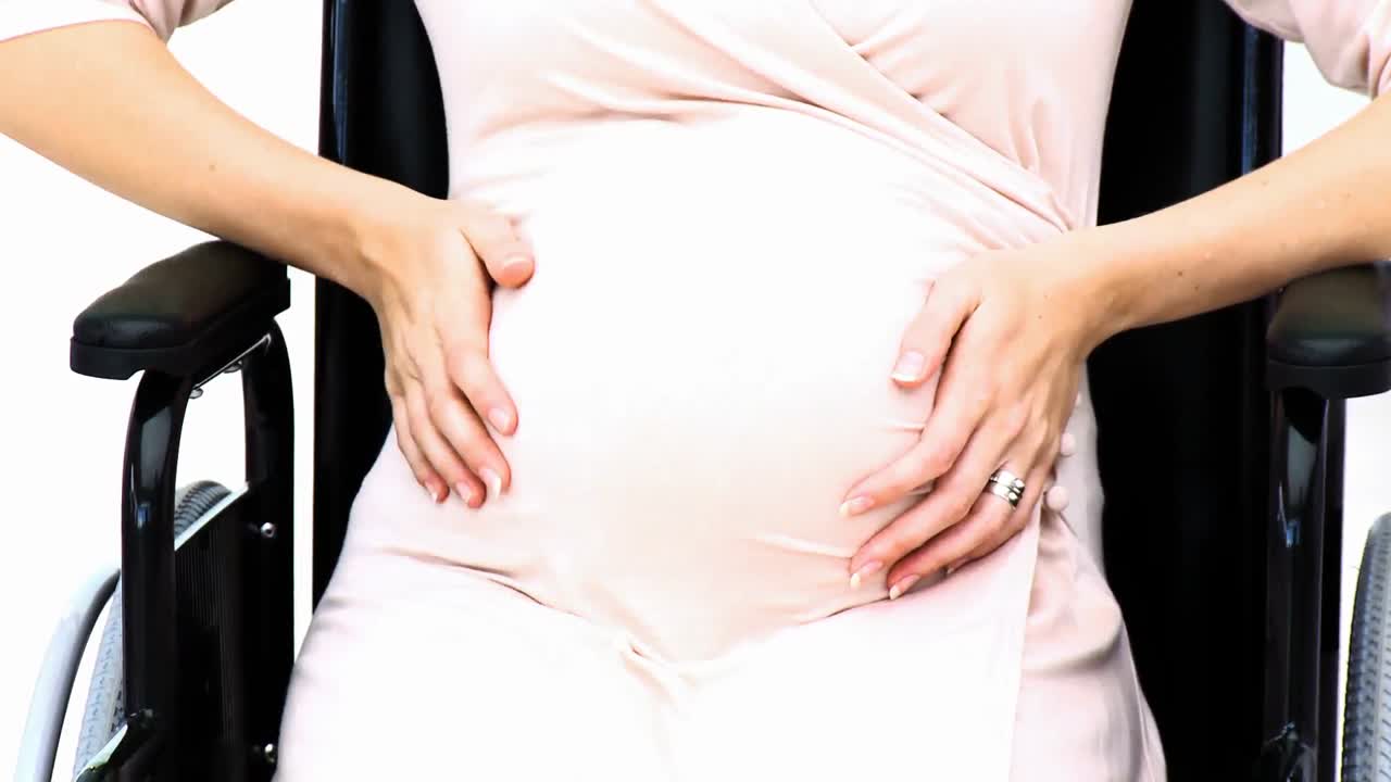 Close up of pregnant woman sitting on wheelchair