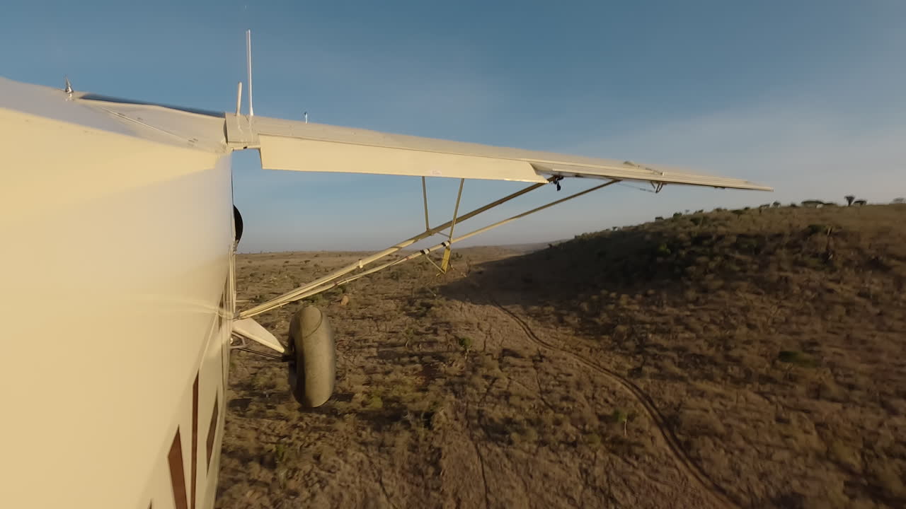 Seitenansicht eines kleinen Flugzeugs über Sträuchern und Felsen