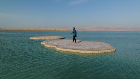 man walks on large slab of solid salt in the dead sea in israel