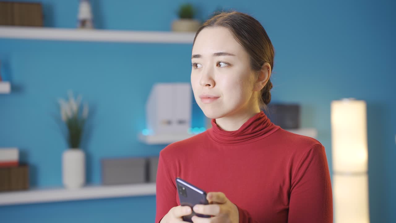 携帯電話を見ながら、何か心配なことを疑っているアジア人女性