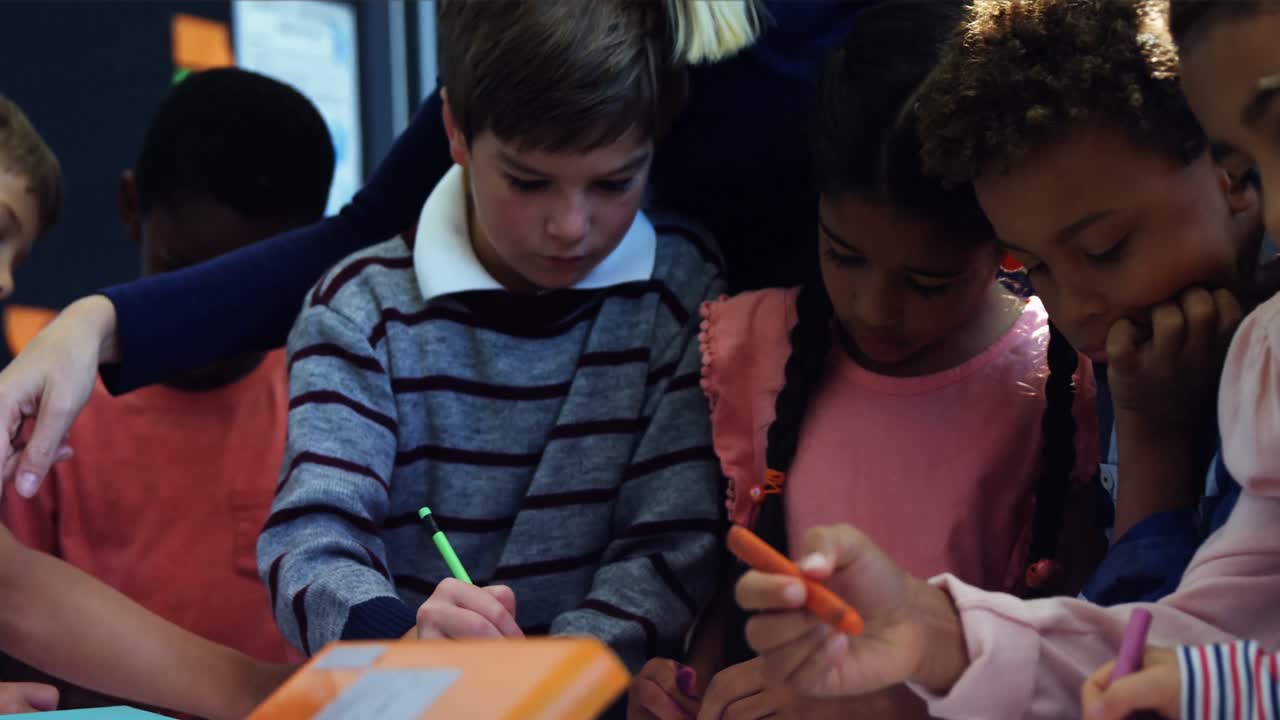 Teacher helping schoolkids with their homework in classroom