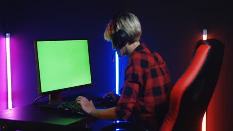 Mujer-Joven-Jugando-En-La-Computadora-Con-Pantalla-De-Clave-De-Croma-En-Una-Habitación-Con-Lámparas-De-Neón-De-Colores-En-La-Pared-1