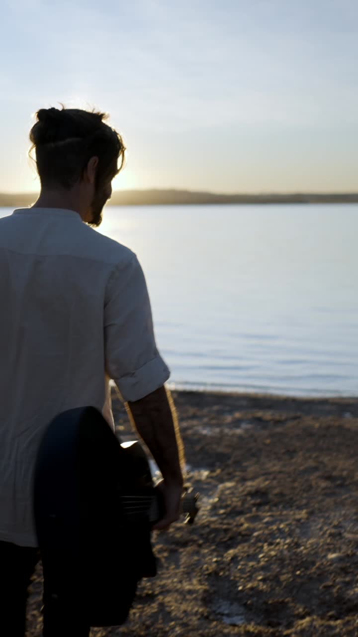 Uomo che cammina con una chitarra al tramonto