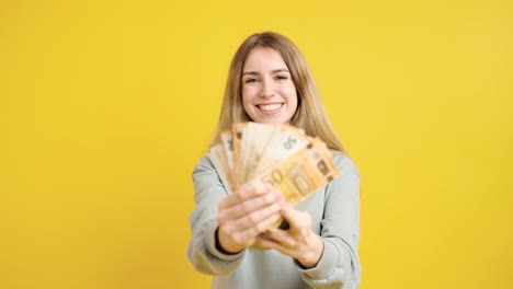 young woman counting brazilian real banknotes on yellow background