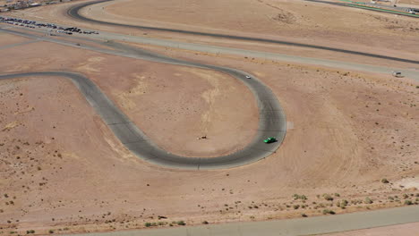 A-race-car-drifts-around-a-hairpin-turn-burning-tires-and-trailing-smoke-plumes---aerial-view