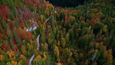 Eine-Kurvenreiche-Straße-Und-Ein-Fluss-Führen-Zu-Einem-Klaren-See,-Der-Die-Lebendigen-Herbstfarben-Der-Berge-Widerspiegelt