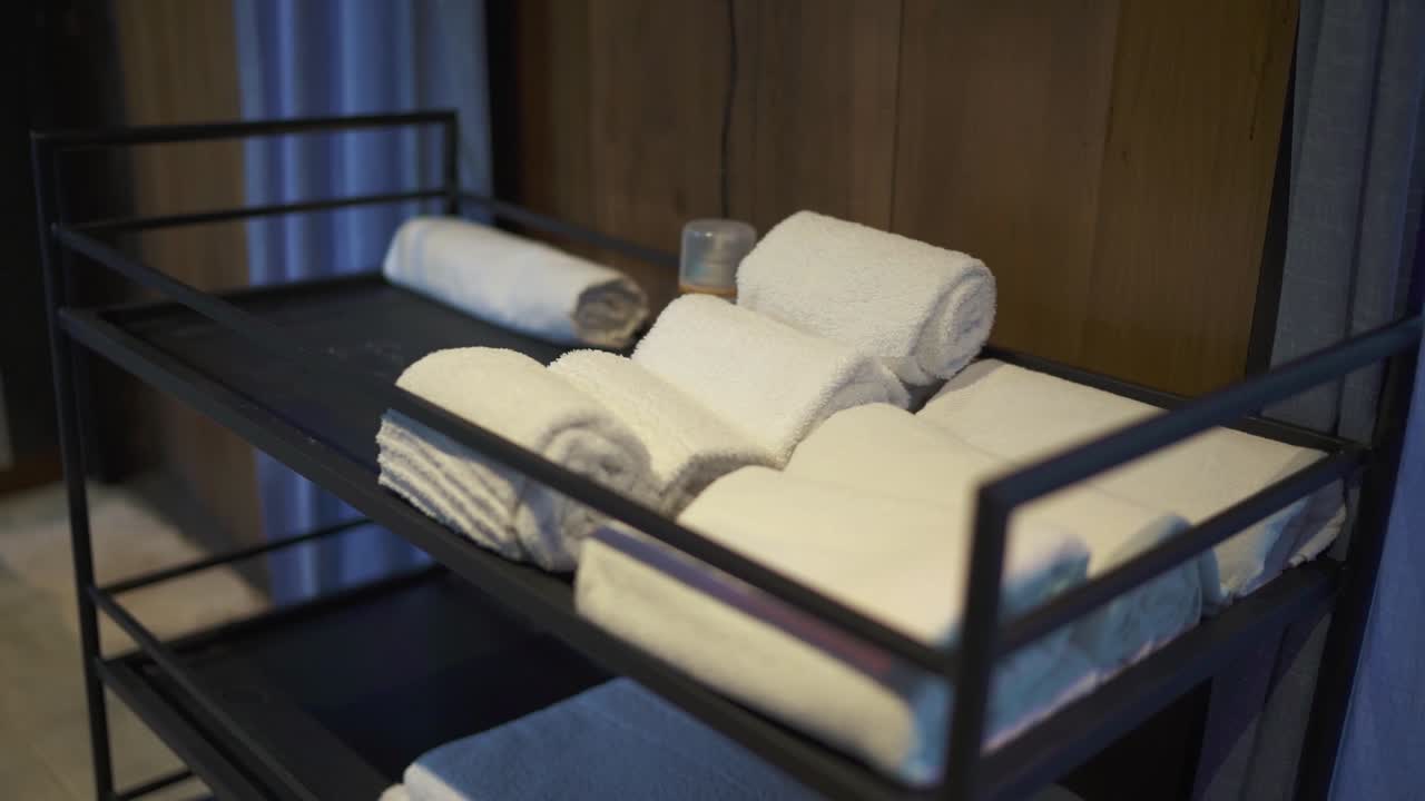 Clean white towels are neatly folded and placed on a metal rack, ready for guests to use, adding a touch of luxury and comfort to the hotel room experience