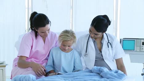 little girl reading with a nurse and a doctor in bed