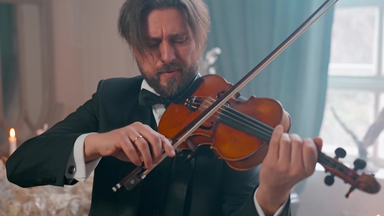 Uomo elegante in smoking che suona il violino con concentrazione