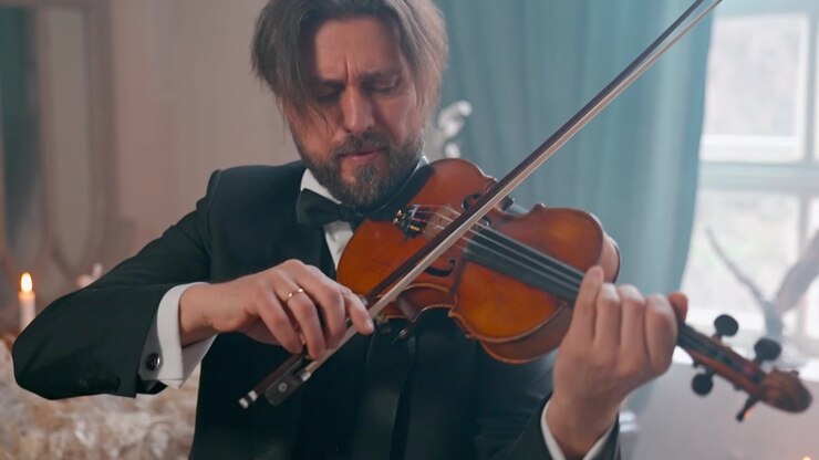 Uomo elegante in smoking che suona il violino con concentrazione