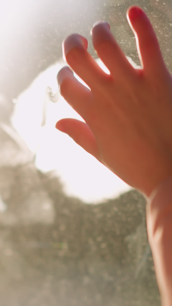 분홍색 모자, 재, 색 겨울 스카프를 입은 어린 소녀가 차에 앉아서 안개가 묻은 창문 유리창을 청소하고 쓰는 창조적인 순간