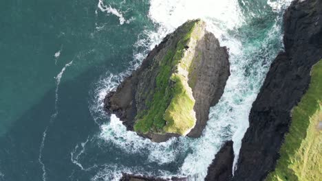 Escarpados-Acantilados-De-Kilkee-Que-Se-Encuentran-Con-El-Atlántico,-Olas-Rompiendo,-Vegetación-Alrededor,-Vista-Aérea