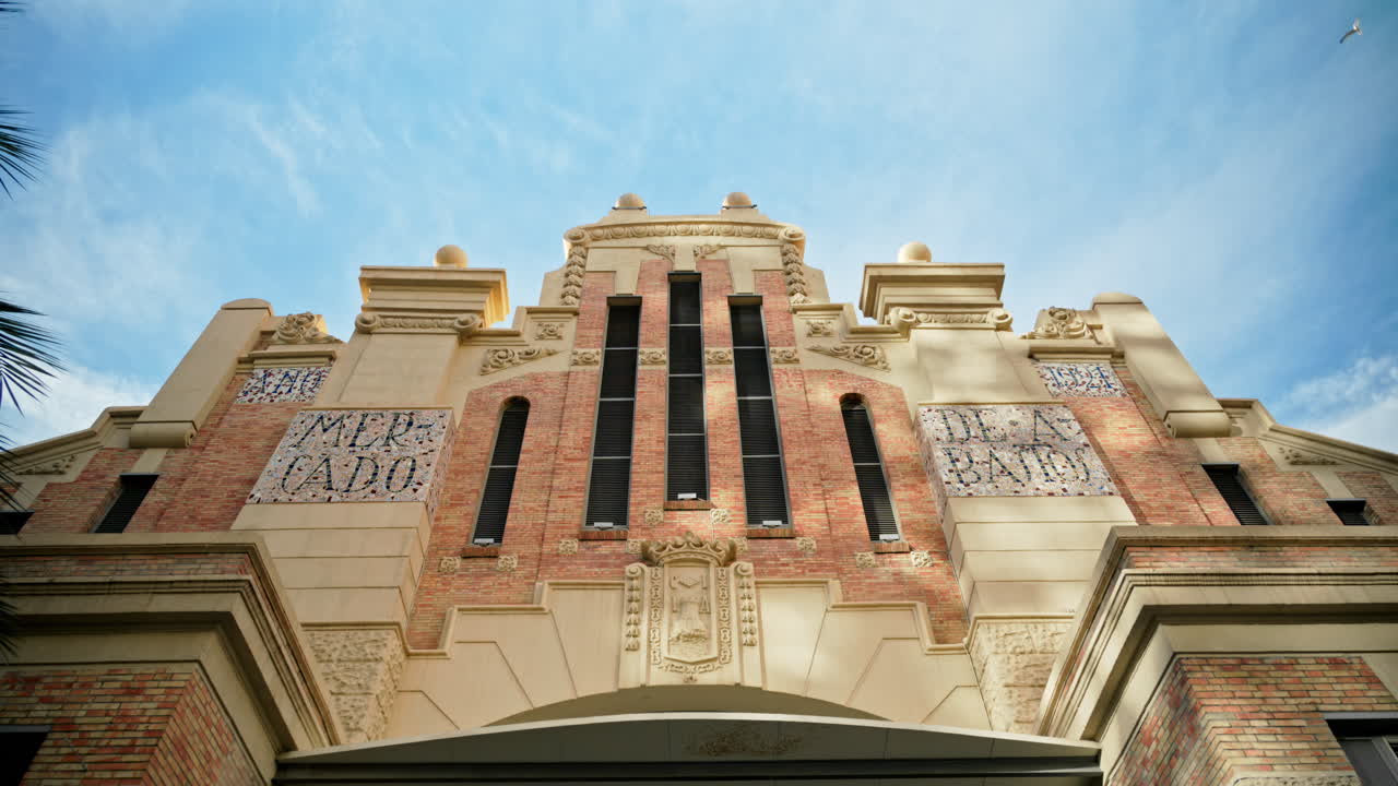 Alicante, Spain - May 23, 2025: Low angle view of a historic market facade cream stone