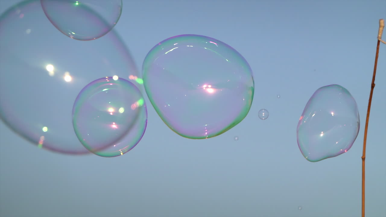 Colorful soap bubbles floating against the blue evening sky during a street performance