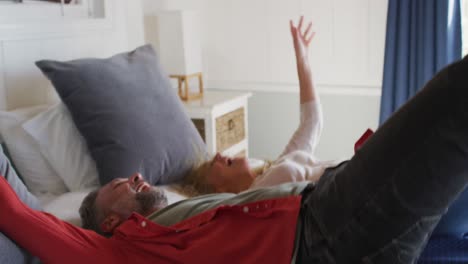 happy caucasian mature couple lying in bed in hotel room