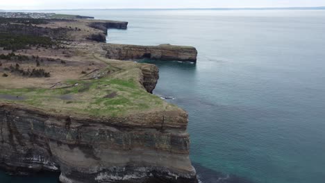 wide drone shot of 300ft cliffs with water below