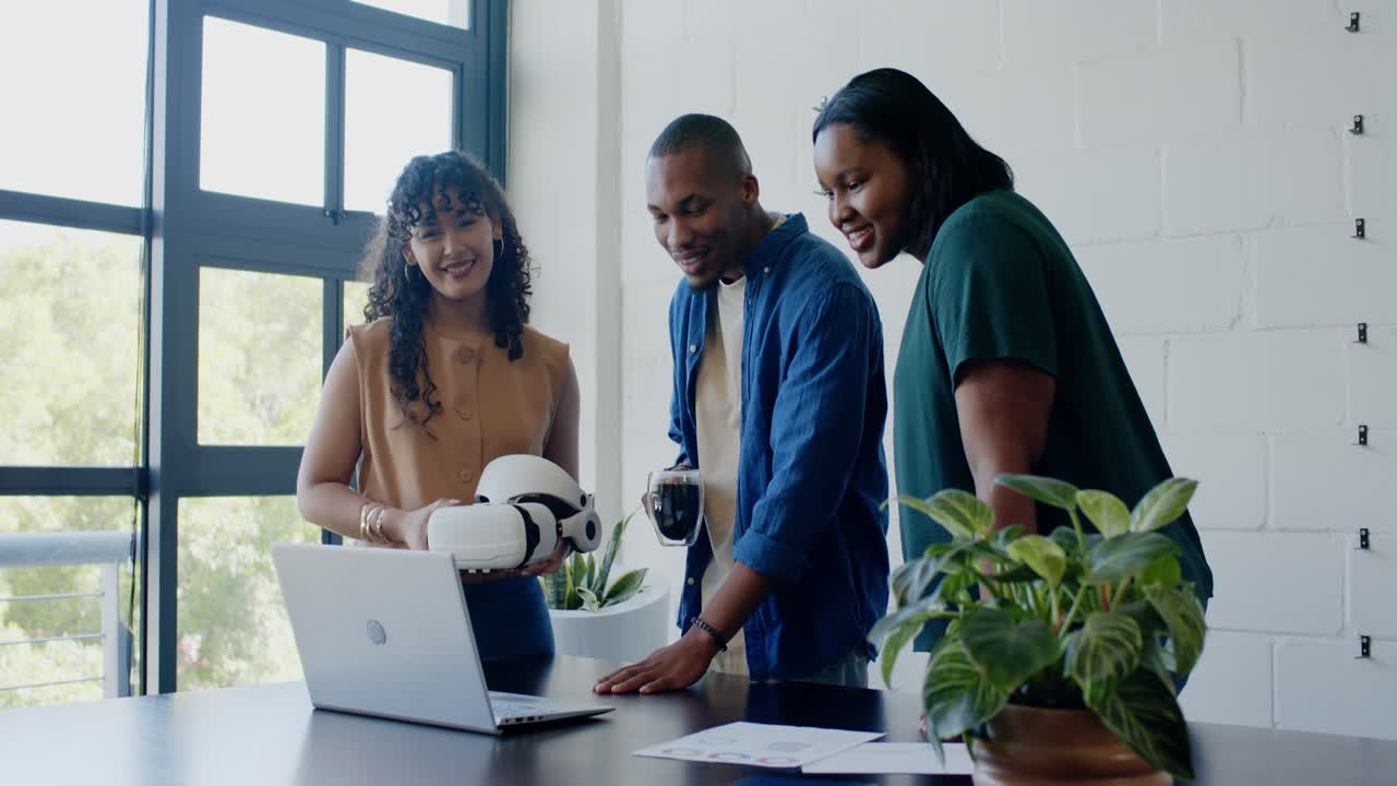 Diverse coworkers leaning in, pointing at laptop after spotting white robot prototype for testing
