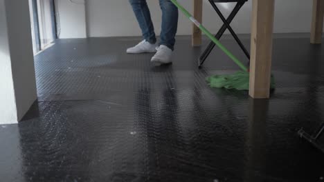 Man-mopping-floor-under-table-in-workplace