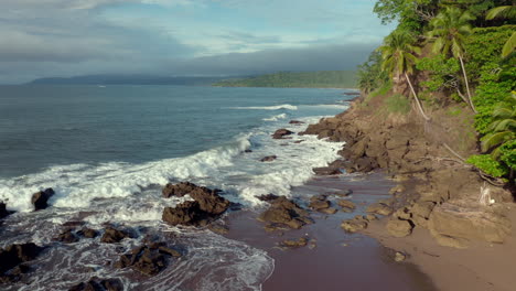 volando bajo a lo largo de la playa rocosa con mar ondulado en tambor, costa rica