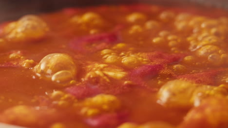 chicken in tomato sauce is boiling on a frying pan with spices. cooking tomato sauce curry with chicken fillet. traditional italian mexican asian dish. high quality studio shot for cafe, restaurant close up.