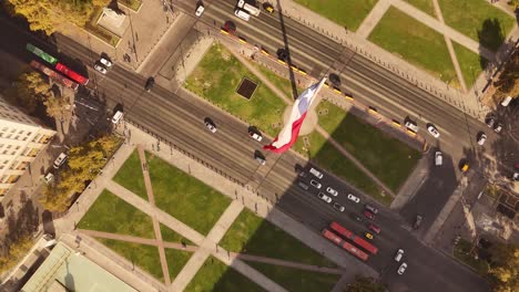 stunning 4k top-down view of de chile's bustling city center, featuring the iconic bandera bicentenario (chilean bicentennial flag) waving majestically. shot in smooth 60fps