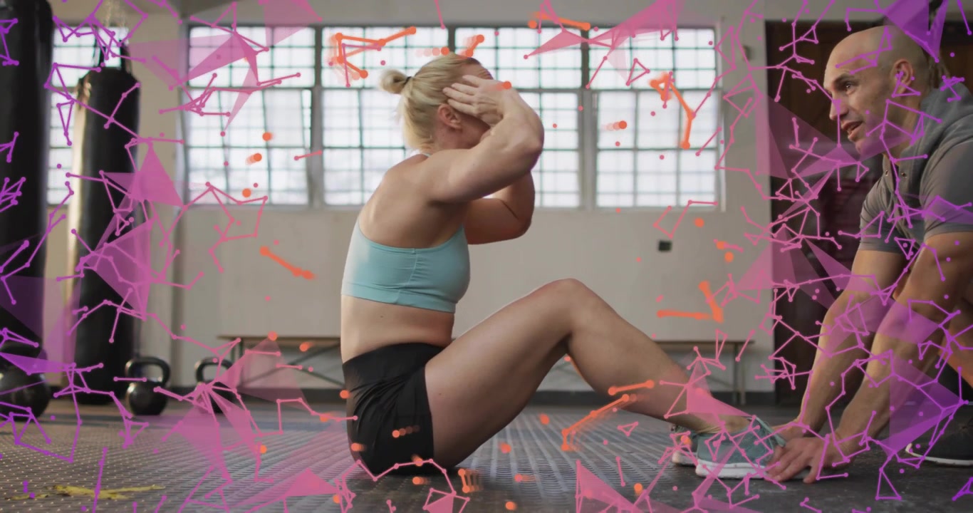 Femme faisant des abdominaux, un entraîneur lui maintenant les pieds, avec des particules rose-orange superposées à l'image pour le fitness.