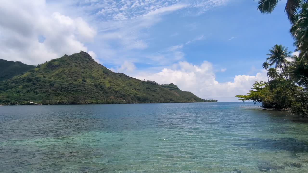 Scenic view of Opunohu Bay, ocean, rugged mountainous terrain, and yachts on tropical Moorea Island in French Polynesia, South Pacific