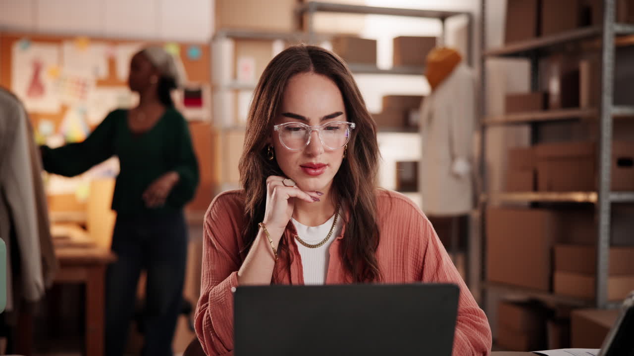 Joven mujer trabajando en su laptop en la oficina de una pequeña empresa.