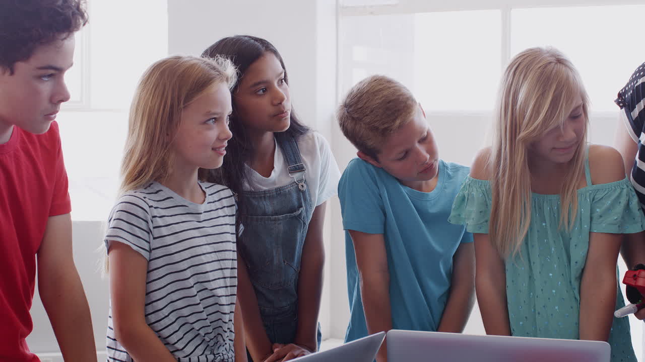 Students With Female Teacher In After School Computer Coding Class Learning To Build Robot Vehicle