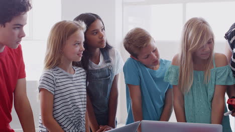 students with female teacher in after school computer coding class learning to build robot vehicle