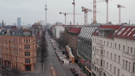 AERIAL:-Slow-flight-through-Empty-Central-Berlin-Neighbourhood-Street-with-Cathedrals-and-view-on-Alexanderplatz-TV-Tower-during-Coronavirus-COVID-19-on-Overcast-Cloudy-Day