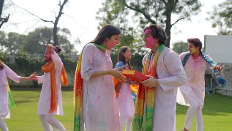 indian man giving a gift to his wife at a holi party