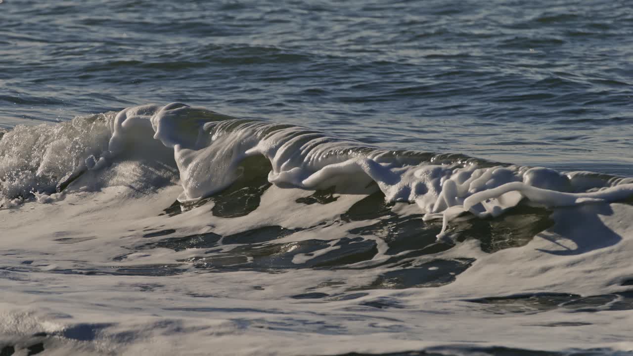 Surging ocean wave with foam at the Oosterschelde storm surge barrier, Zeeland, super slow motion