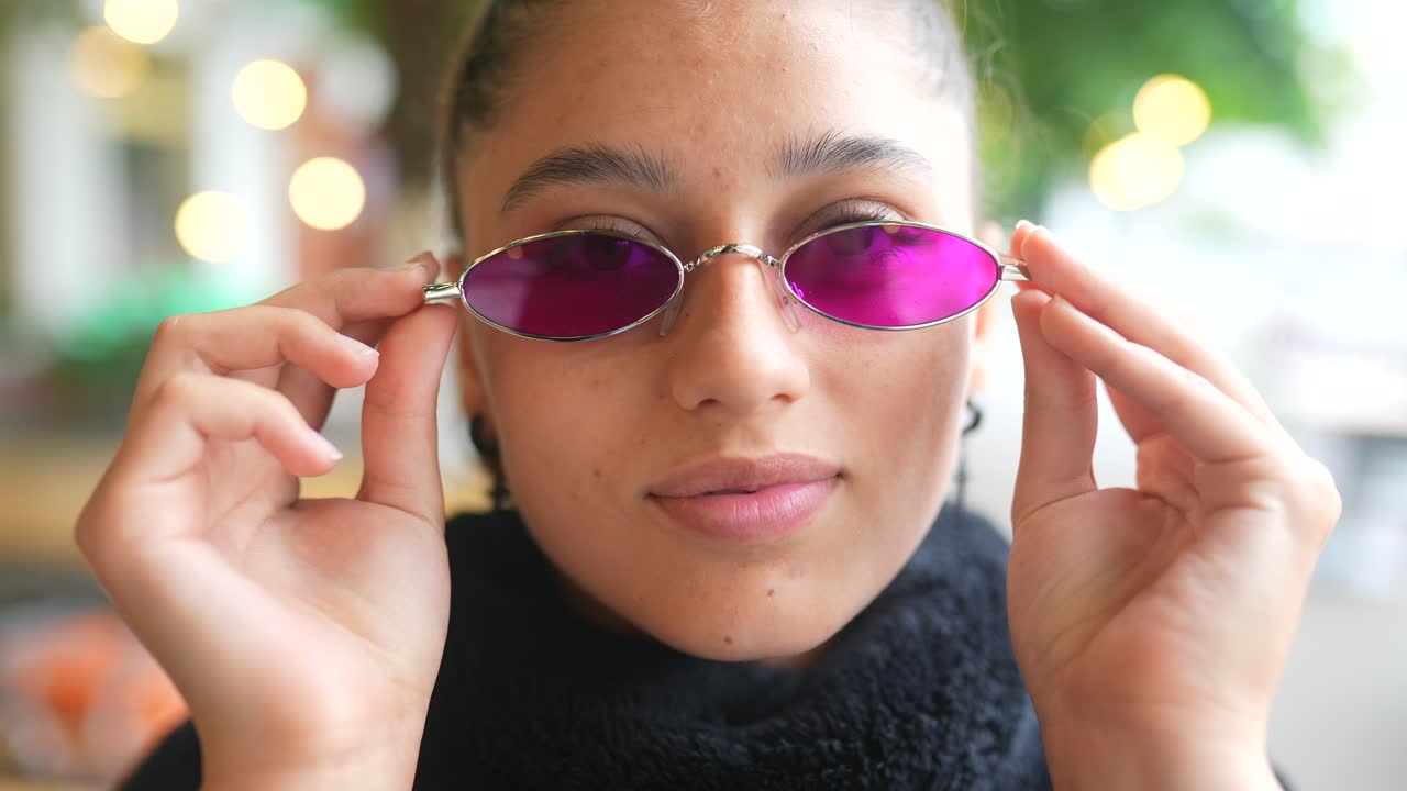 una mujer joven con gafas de sol rosas.