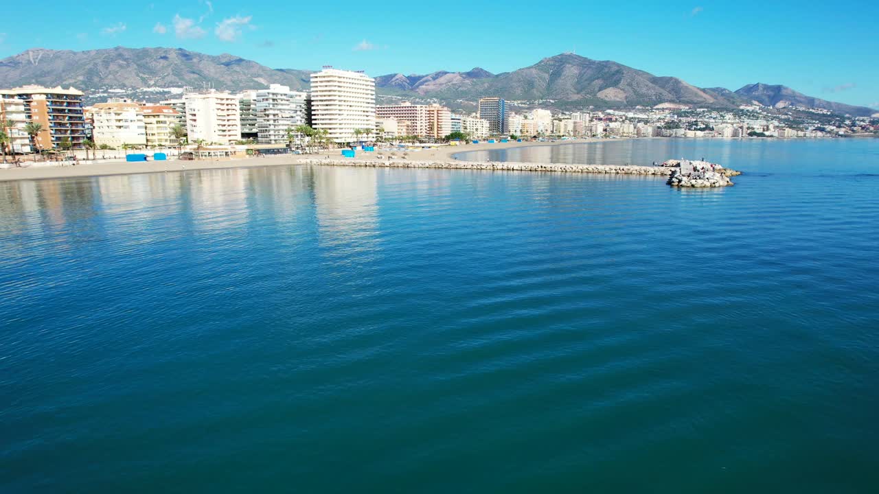 dolly aéreo hacia el muelle de roca por la playa de fuengirola hills