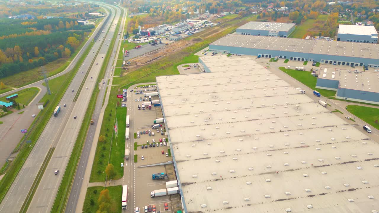 Edificios de centro logístico, almacenes cerca de la autopista, vista desde la altura, un gran número de camiones en el estacionamiento cerca del almacén.