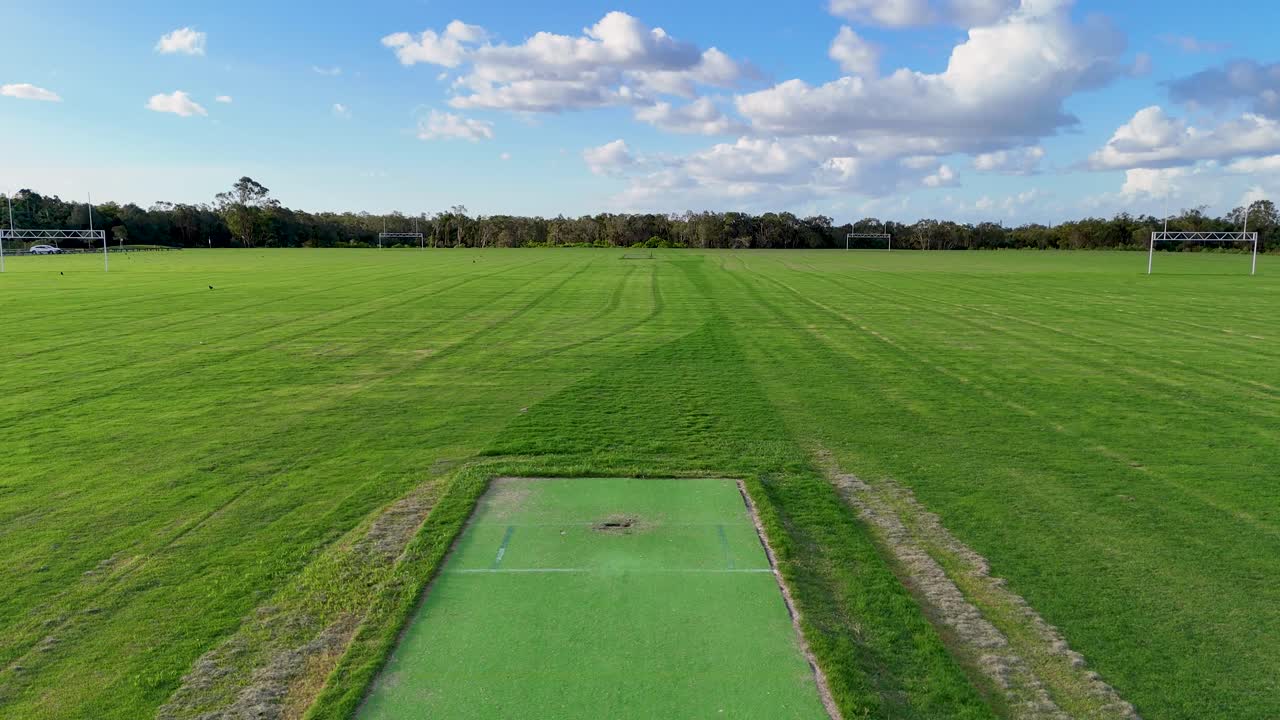 Aerial view of a sports field with a cricket pitch, captured by drone under clear skies on the Gold Coast