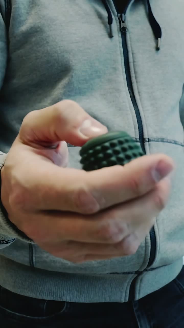 Primo piano di mani che stringono una palla da massaggio con punte