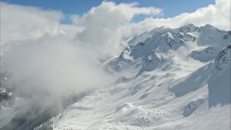 Snowy-mountain-shrouded-in-clouds-on-sunny-day