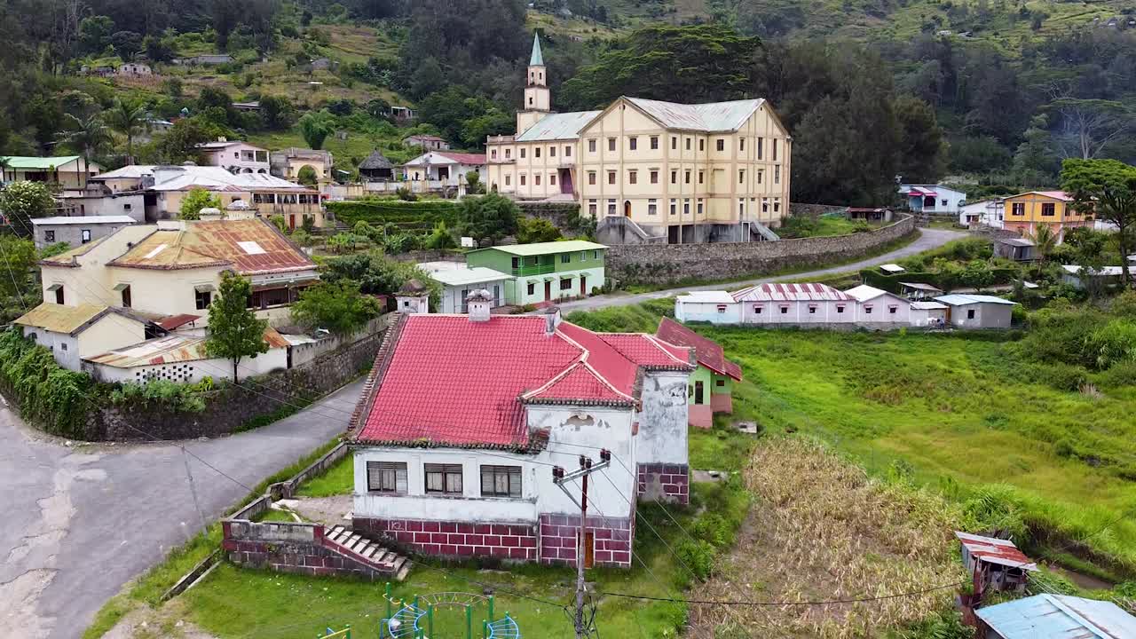 vista aérea de drones del parque infantil, casas y una hermosa iglesia en el campo rural montañoso de la ciudad de maubisse en el distrito de ainaro, timor leste en el sudeste asiático
